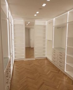 an empty room with white shelves and drawers on either side of the closet, light shining through