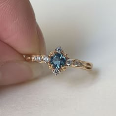 a person is holding a blue and white diamond ring in their left hand while the other hand holds it