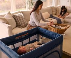 a woman sitting on a couch next to a baby in a crib