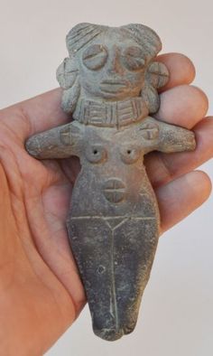 a hand holding a small stone figurine in it's palm