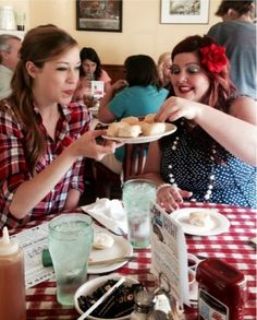 two women sitting at a table with plates of food