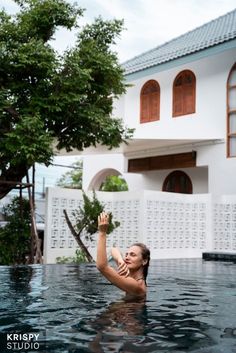 a woman in the water reaching up to catch a frisbee with her hand