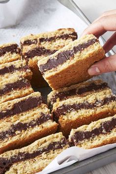 a person is picking up some cake from a pan filled with it's chocolate frosting