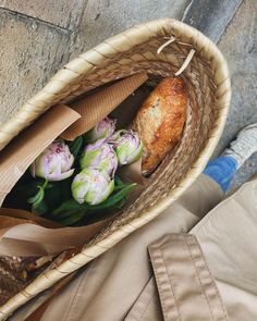 a basket filled with bread and flowers on the ground