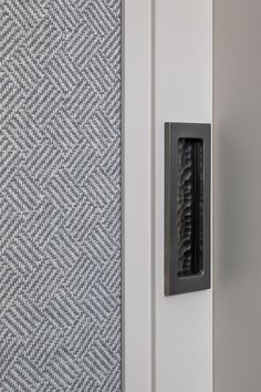 a close up of a door handle on a white and grey door with a checkered pattern