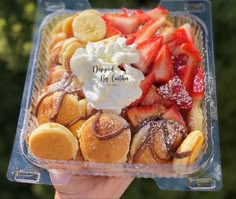 a person holding up a plastic container filled with desserts and pastries on top of it