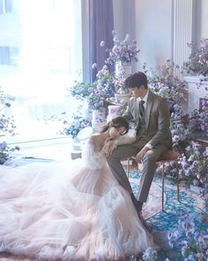 a man and woman sitting on a bench in front of flowers