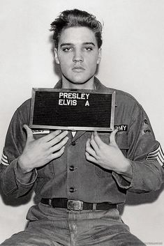 elvis presley holding up a sign with the words pressley elvis a on it in front of his face