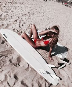 a woman laying on the beach with her surfboard