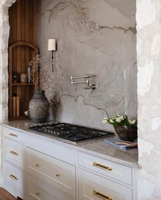 a stove top oven sitting inside of a kitchen next to a wall mounted faucet