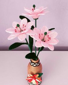 pink flowers are in a vase on a white tablecloth with an ornament