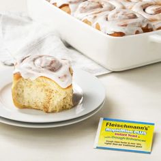 a white plate topped with cinnamon rolls next to a box of frosted doughnuts