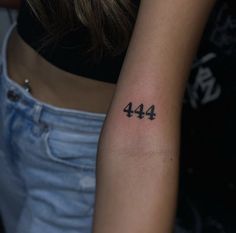 a woman's arm with the number forty four tattoo on her left arm, which is written in black ink