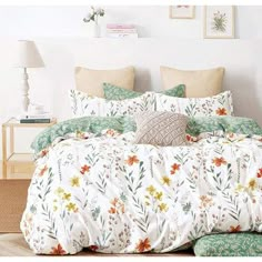 a bed with white and green floral comforters