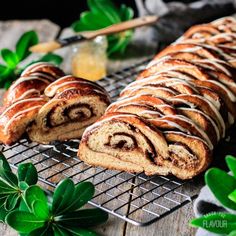 cinnamon roll sitting on top of a cooling rack next to some leaves and a cup