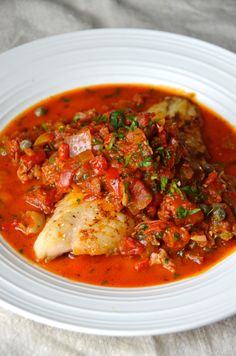 a white plate topped with fish covered in tomato sauce