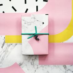 a gift wrapped in pink and white paper with a green ribbon on top of it