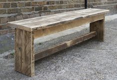 a wooden bench sitting in front of a brick wall