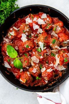 a skillet filled with meatballs covered in marinara sauce and parmesan cheese