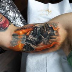 a man's arm with a skull on it and flames coming out of the water