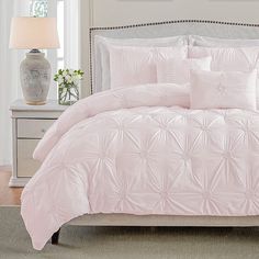 a bed with pink comforter and pillows in a room