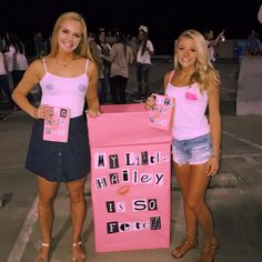 two women standing next to each other holding signs