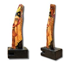 two wooden sculptures with faces on them sitting next to each other in front of a white background