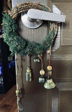 a wreath with bells hanging from it's side on a door handle and some other decorations