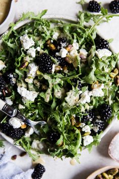 a salad with blackberries and feta cheese in a bowl