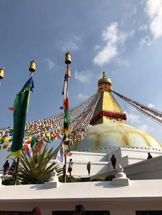 many flags are flying in the air near a large white building with a gold dome