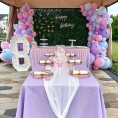 a purple and white birthday party with balloons