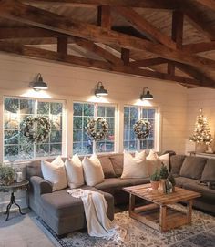 a living room with couches and christmas wreaths on the windows, lights hanging from the ceiling