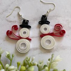 two pairs of red, white and black earrings sitting on top of a marble table