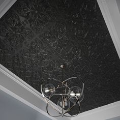 a chandelier hanging from the ceiling in front of a black wallpapered ceiling