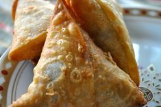 three fried pastries on a plate with red and white designs