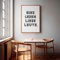 two chairs and a table in front of a window with a poster on the wall