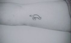 a person's arm with a small turtle tattoo on the left side of their arm