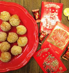 a red plate topped with lots of cookies next to chinese paper and coins on a table