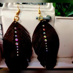 pair of brown feather earrings with beads hanging from hooks in front of white oven door