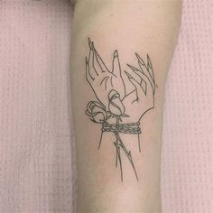 a tattoo on the leg of a woman with hands tied up and flowers in it