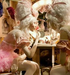 two mannequins dressed in pink sitting next to each other near a mirror