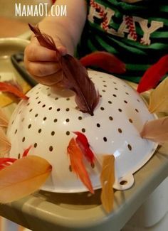 a child is sitting in a high chair and playing with leaves