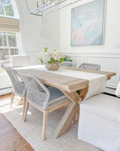 a dining room table with chairs and a vase on top of it in front of a window