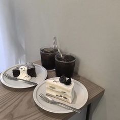 two pieces of cake on white plates with forks and spoons next to each other