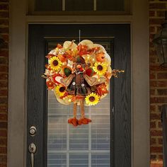 a wreath with sunflowers and leaves hanging from it's side on the front door