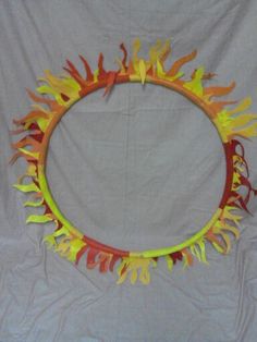 an orange and yellow fire ring made out of paper on a white sheeted background