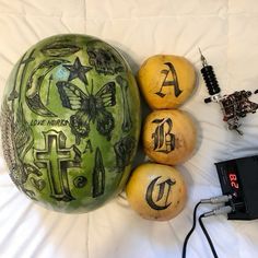 a watermelon with some writing on it next to three oranges and an electronic device