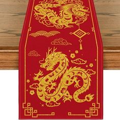 a red table runner with gold dragon design on the front and sides, hanging from a wooden wall