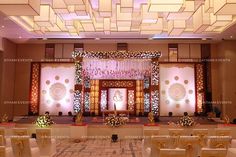 a banquet hall decorated with white and gold chairs, floral decorations and chandeliers