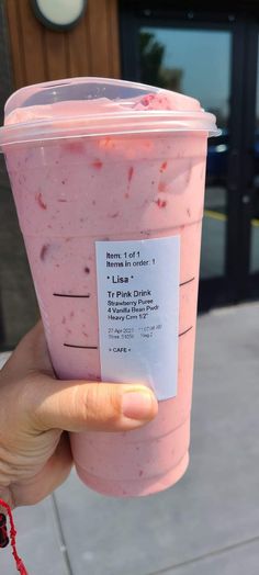 a person holding up a pink drink with a label on it's cup sleeve